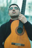 man holding brown acoustic guitar