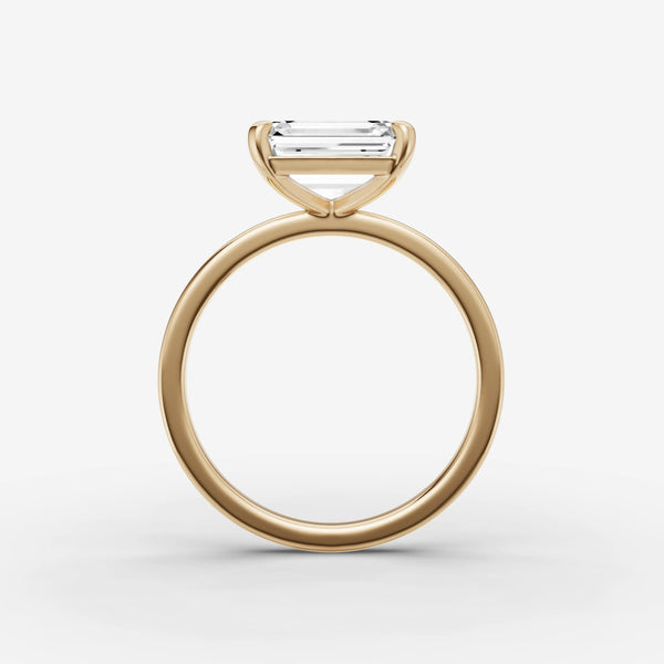 Side profile of east-west emerald cut solitaire ring setting in yellow gold