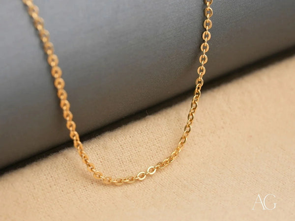 Close-up of delicate 18K gold chain necklace showing small oval link details