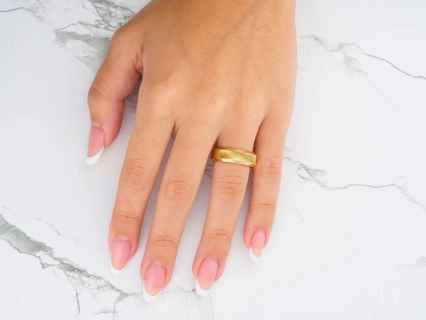 Side view of gold wedding band with geometric cross-hatch texture