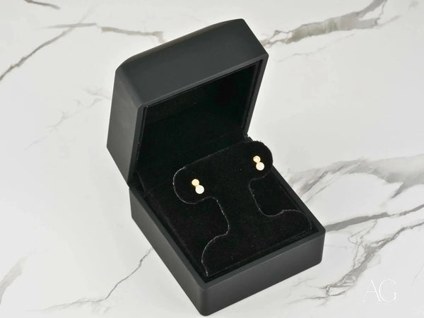 Open black jewelry box with Lustrous Harmony 18K gold pearl drop earrings