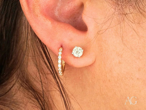 Womans ear with 18k yellow gold mini hoop and CZ stud earrings