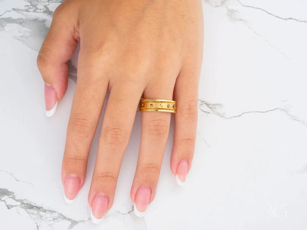 Royal Crest gold band ring with textured accents and embedded crystals on finger