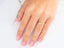 Gold band ring on hand with French-tipped nails showcasing timeless 18k yellow gold jewelry