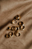 A collection of 18k gold rings featuring smooth and engraved designs with a white stone inlay in fine jewelry style.