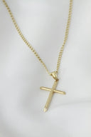 A gold cross necklace on a mannequin