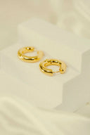 a pair of gold earrings sitting on top of a white surface