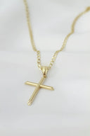Gold cross pendant with subtle diamond accents on a delicate chain from art gold jewelry collection.