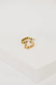 a pair of gold earrings sitting on top of a white box