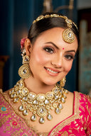 A smiling woman adorned in traditional indian jewelry and attire.