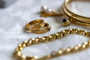 Golden jewelry is arranged on a soft white surface.