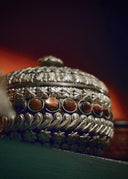 Silver ornate box with intricate floral embossing and warm amber stones featured in fine jewelry and art gold fashion.