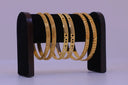 Several gold bangles displayed on a stand.