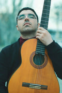 man holding brown acoustic guitar