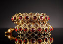 Gold jewelry art gold fine jewelry gold-toned bangle with red and brown gemstones in intricate circular metalwork