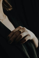 A sleek minimalist 14k gold ring with a smooth rounded band worn on the middle finger showcasing fine jewelry.