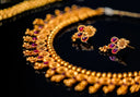 Gold necklace with intricate floral designs and embedded rubies featured in a beginner’s guide at an everett jewelry store