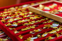 Gold charms of fine jewelry crafted in 18k gold displayed in a red velvet tray behind the cultural veil article