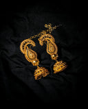 Golden paisley-patterned jhumka earrings with intricate filigree work and dangling charms in art gold jewelry design