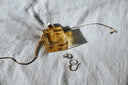 A square amber glass perfume bottle with metallic cap on textured fabric in an everett jewelry store setting.