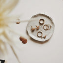 White ceramic ring dish with scalloped edge and embossed pattern for essential jewelry cleaning of engagement ring and art gold jewelry