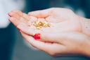 A hand with red nail polish holds shimmering gold glitter illustrating jewelry care tips for 18k gold jewelry.