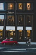 A vibrant red classic Porsche sports car parked outside Cartier boutique in an article on engagement rings and wedding bands.