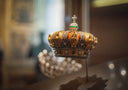 A regal gold crown jewel adorned with intricate detailing, emerald stones, and sparkling diamonds in fine gold jewelry.