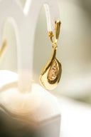 A delicate gold teardrop earring with a faceted rose gold inset stone complements 18k gold chain jewelry styles