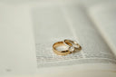 Gold wedding band with a single diamond and simple gold ring in 18k gold fine jewelry on an open book