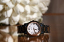 A sleek chopard watch with a white dial roman numerals and black and rose gold bracelet in fine gold jewelry.