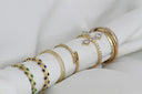 A collection of 18k gold rings with diamonds and emerald accents displayed on a white napkin for gold jewelry care.