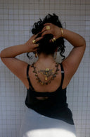 Woman with tattoo and jewelry poses against tiled wall