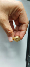 A person holding a gold ring in their hand