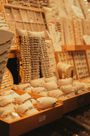 Gold-toned chain bracelets displayed on white cushioned stands in wooden trays showcasing art gold jewelry in massachusetts