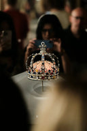 Ornate crown displayed with people taking photos