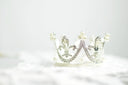 A delicate silver tiara with rhinestones and pearls showcasing crown jewels in timeless art gold jewelry traditions.