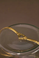 a gold necklace in a glass bowl on a table