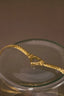 a gold necklace in a glass bowl on a table