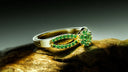 A delicate gold jewelry ring with vibrant green emeralds in a floral design for fine art gold jewelry collections.