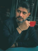 man in black suit holding red ceramic mug