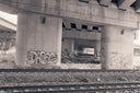a train track under a bridge with graffiti on it