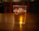 A glass of beer on a wooden table.