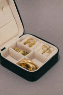Black velvet jewelry case with cream interior holding gold-toned rings and bracelets showcasing fine gold jewelry.