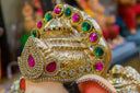 A golden crown with intricate details and vibrant pink and green gemstones showcases 18k gold jewelry elegance.