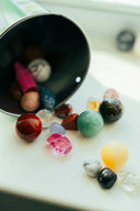 A collection of colorful polished gemstones spilling from a container highlighting famous cursed gems in art gold jewelry and engagement rings