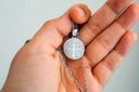 Silver saint benedict medal pendant on a delicate chain symbolizing fine jewelry and cultural talisman significance.