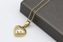 Gold heart-shaped pendant necklace with six clear gemstones in polished metal finish for fine jewelry trends