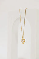 A delicate 18k gold jewelry necklace with a heart-shaped pendant featuring a clear faceted crystal center.