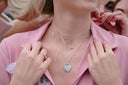 Silver diamond heart necklace layered over delicate chains